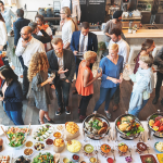 A group of people standing around a table with food.