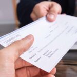 A person holding onto a check from the company